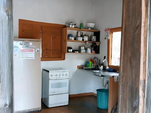 a kitchen with a white refrigerator and a sink at Camping Avohai in São Thomé das Letras