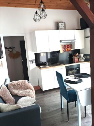 une cuisine avec des armoires blanches et une table et des chaises dans l'établissement Fleurs de Lys, à Friville-Escarbotin