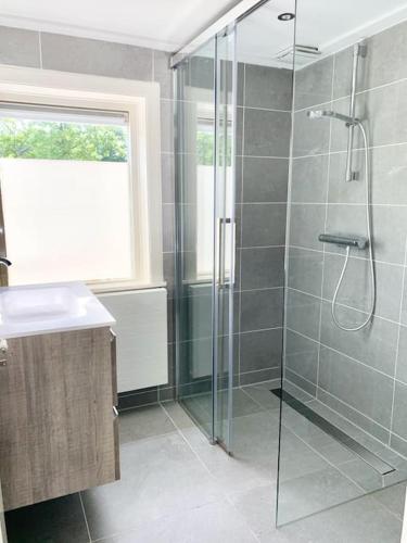 a bathroom with a glass shower with a sink at Charming villa,central location,train and bus nearby in Soest