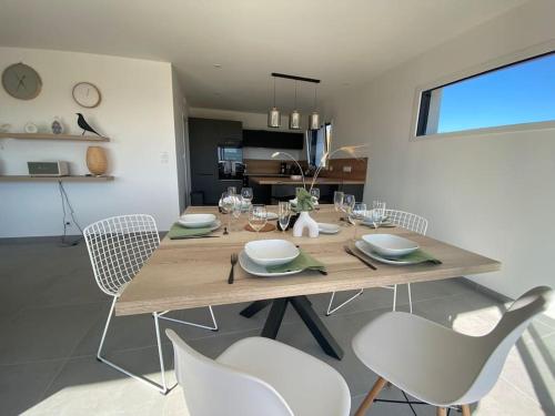 Un comedor con una mesa de madera y sillas blancas. en Maison neuve vue panoramique sur la mer 6 pers à Crozon, en Crozon
