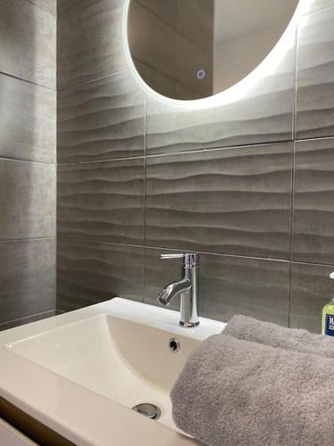 La salle de bains est pourvue d'un lavabo et d'un miroir rond. dans l'établissement Maison neuve vue panoramique sur la mer 6 pers à Crozon, à Crozon