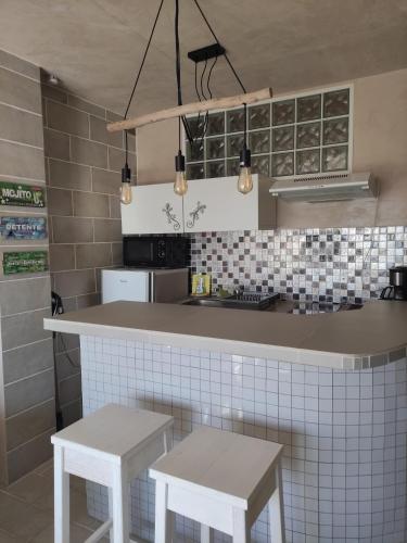 une cuisine avec un comptoir et deux tabourets blancs dans l'établissement Studio vue mer, à Cagnes-sur-Mer
