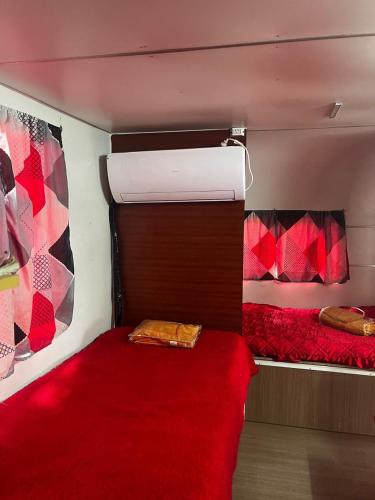 a bedroom with two beds and a red comforter at Bungalow Sobre Ruedas Viento Potro in San Miguel del Monte