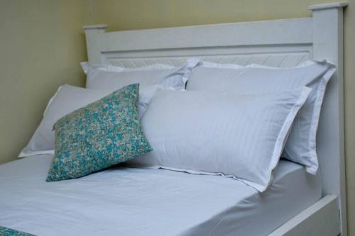 a white bed with white pillows and a green pillow at Tala Cosy Homes in Tawa