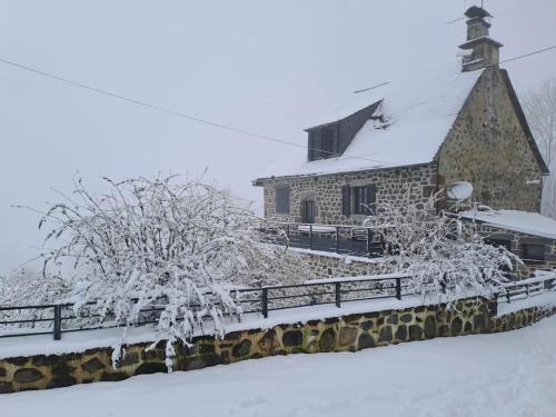 une église recouverte de neige à côté d'une clôture dans l'établissement Maison Auvergnate, à Pailherols