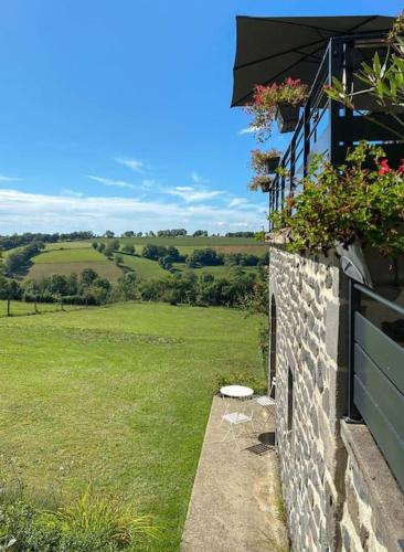 - un bâtiment en pierre avec une fenêtre fleurie dans l'établissement Maison Auvergnate, à Pailherols