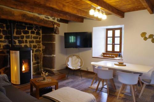 un salon avec une table et une cheminée dans l'établissement Maison Auvergnate, à Pailherols
