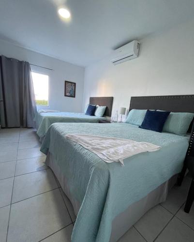 a bedroom with two beds with blue sheets and a window at Hotel Boutique Los Pinos in Santa Rosa de Copán
