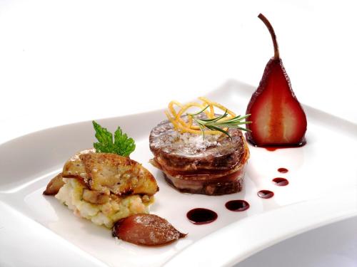 a plate of food with meat and a pomegranate at Perla, Resort & Entertainment in Nova Gorica