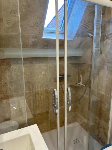 une douche avec une porte vitrée dans une salle de bain dans l'établissement VILLA LES ROSES Maison 5 Couchages, à Offranville