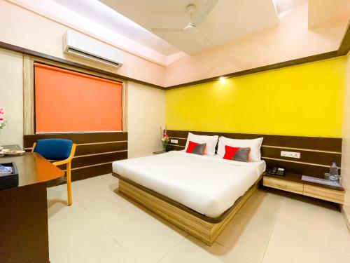 a bedroom with a bed and a desk and a yellow wall at Hotel Golden Treat in Indore