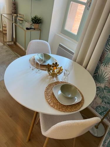 une table blanche avec une assiette et des verres sur elle dans l'établissement Le Bohème Tourisme Repos Business à Toulouse, à Toulouse
