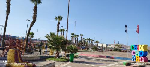 a park with a playground with palm trees and a play park at Departamento Full 3D 2B Cerca de Playas en Arica in Arica