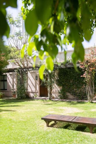 a wooden bench sitting in the grass in front of a house at Hotel Salta in Salta