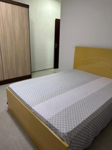 a bedroom with a bed and a wooden cabinet at Casa 70mt2 Mobiliada Centro Gaivota 400mt do Mar Wifi TV Smart in Balneário Gaivotas