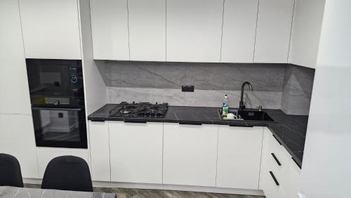 a white kitchen with a stove and a sink at AIRPORT&APARTMENT&parking in Chişinău