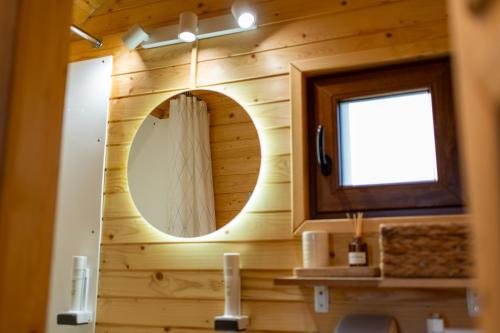 a bathroom with a round mirror in a wooden wall at Glamp In Style Pods Resort in Bran