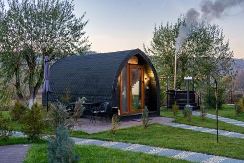 a black roofed tent in a garden with trees at Glamp In Style Pods Resort in Bran