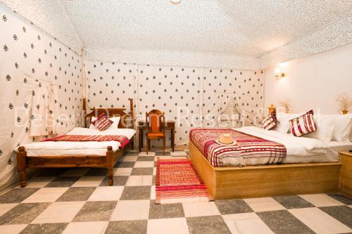 a bedroom with two beds and a checkered floor at Desert Dream Royal Camp & Pool in Jaisalmer