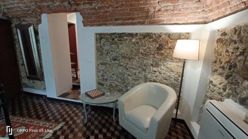 a room with a white chair and a stone wall at ZuccarelloDreams in Zuccarrello