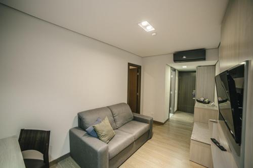 a living room with a couch and a television at Interludium Iguassu Convention Hotel in Foz do Iguaçu