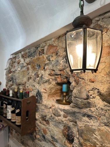 a lamp hanging on a stone wall with a shelf at ZuccarelloDreams in Zuccarrello