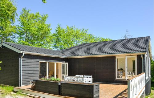 a small black house with a wooden deck at Cozy Home In Hundested With Wifi in Hundested