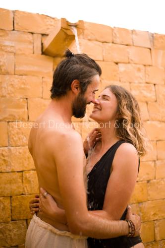 a man and a woman standing in front of a brick wall at Desert Dream Royal Camp & Pool in Jaisalmer