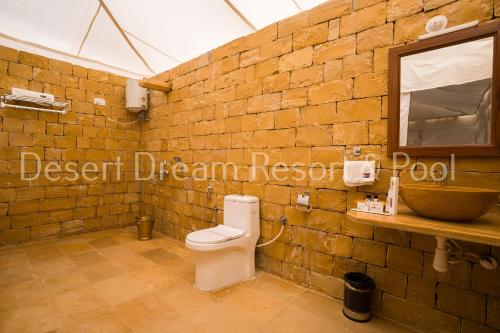 a bathroom with a toilet and a brick wall at Desert Dream Royal Camp & Pool in Jaisalmer