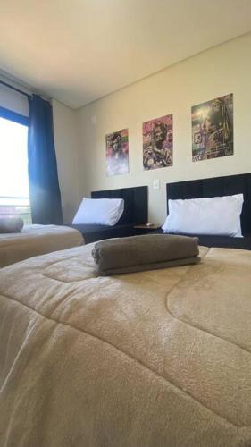a room with two beds with posters on the wall at Stúdio de 1 Quarto, Wifi 500mb, Condominio com Elevador, 1 Vaga de Garagem, Cozinha Completa - Indicado para Grupos, Hospedes a Trabalho, Família e Pets in Toledo