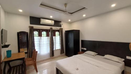 a bedroom with a bed and a desk and window at Hotel Santi Palace in Bokakhat