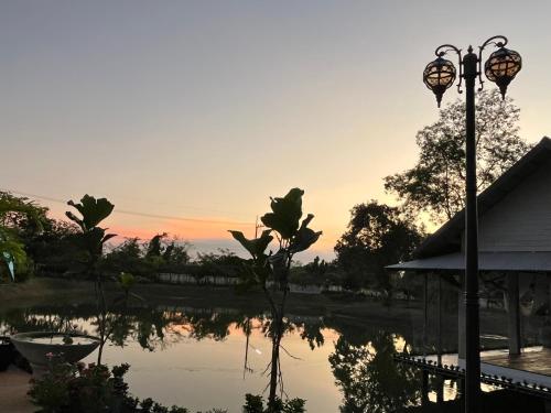 a sunset over a pond with a street light at Cozy breezing countryside Pet in Ban Khlong Sip Sam Lang