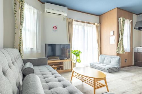 a living room with a couch and a tv at 江の島Home II in Kugenuma
