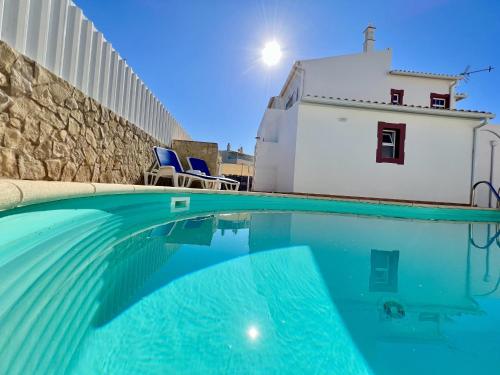 a swimming pool with blue chairs and a building at Pera Stylish Villa With Pool by Homing in Pêra