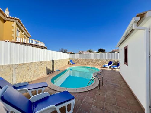 a swimming pool with blue chairs and a swimming pool at Pera Stylish Villa With Pool by Homing in Pêra