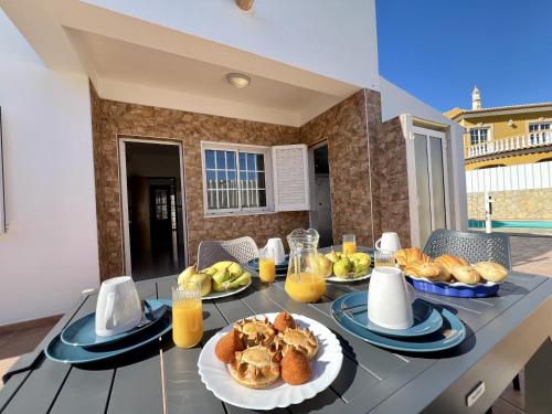 a table with plates of food and orange juice at Pera Stylish Villa With Pool by Homing in Pêra