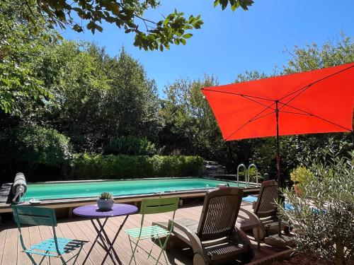 une terrasse avec une table, un parasol rouge et une piscine dans l'établissement L Étoile du Sud, à Sète