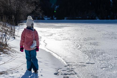a girl is walking on a frozen lake in the snow at DAS GERSTL Family Retreat in Resia