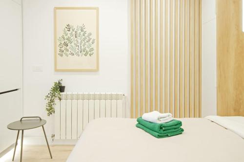 Un dormitorio con una cama blanca con toallas verdes. en Designers Apartment - chic choice for the stay, en Iaşi