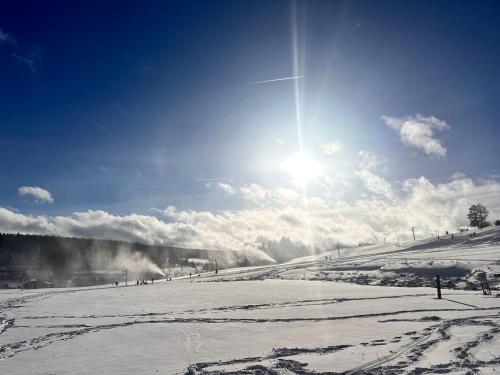 a snow covered slope with the sun in the sky at 1065 metrů nad mořem in Kvilda