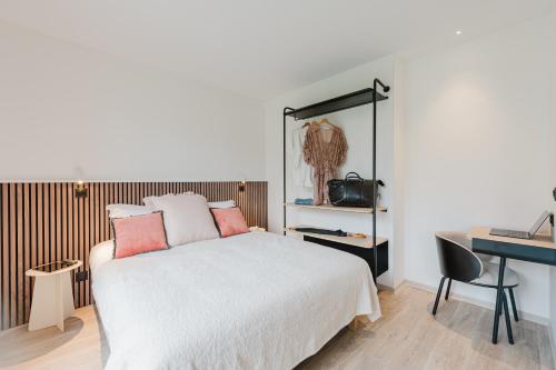 a bedroom with a white bed with a desk and a computer at Appart Hotel Neostelia in Annecy