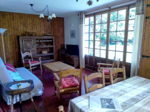 un salon avec une table, des chaises et des fenêtres dans l'établissement Chalet au bord du lac, à Saint-Jorioz
