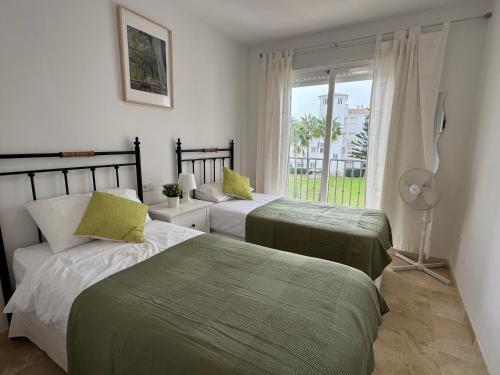 two beds in a room with a window at Casa Feliz - Stunning 2 bed Penthouse in Manilva with pool, sea and mountain views, close to the beach and facilities in Manilva
