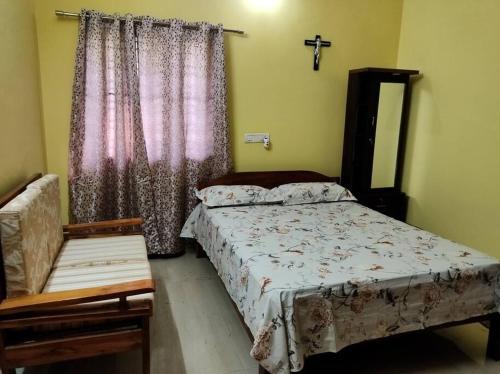 Un dormitorio con una cama y una silla y una ventana. en Carmel Villa in a gated community, en Secunderābād