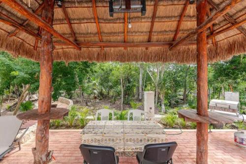 a patio with a table and chairs in a straw umbrella at Habitación 1 Cama King, Tulum Country Home, con Muelle de Pesca, Club de Playa, Alberca, Cenote y Campo de Golf, Contrata Day Pass Bahia Principe in Akumal