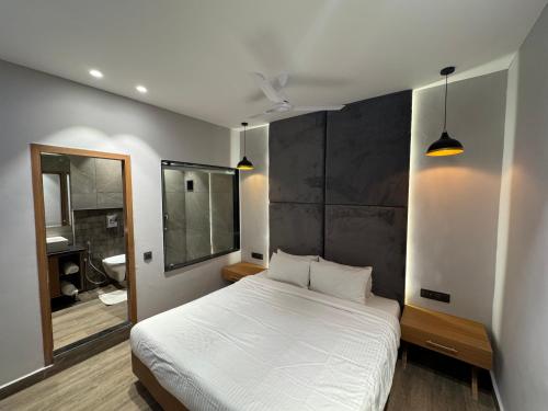 a bedroom with a large white bed and a mirror at The Beach House Candolim in Candolim