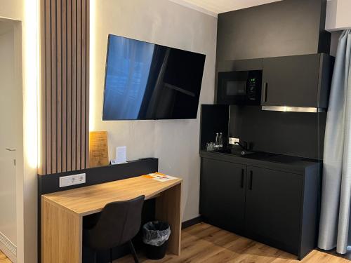 a room with a desk and a tv on the wall at Hotel Senator in Bielefeld