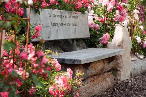 a stone bench sitting on a rock with flowers at Charmehotel Uhrerhof - Deur in Ortisei