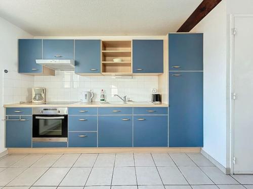 Il comprend une cuisine avec des placards bleus et du carrelage blanc. dans l'établissement Spacieux 2 pièces en duplex, à Villelongue-de-la-Salanque