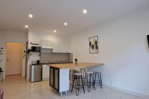 une cuisine avec un comptoir et quelques tabourets dans l'établissement Superbe appartement Intra-Muros, à Avignon